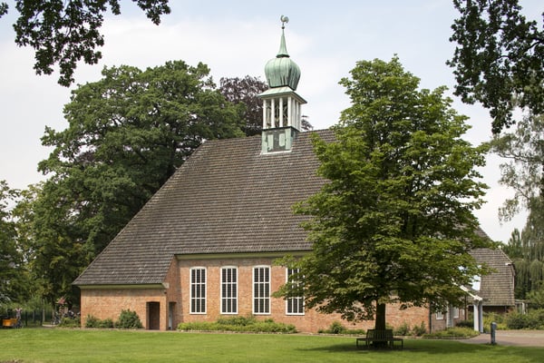 Das Kirchengebäude von Bäumen umringt.
