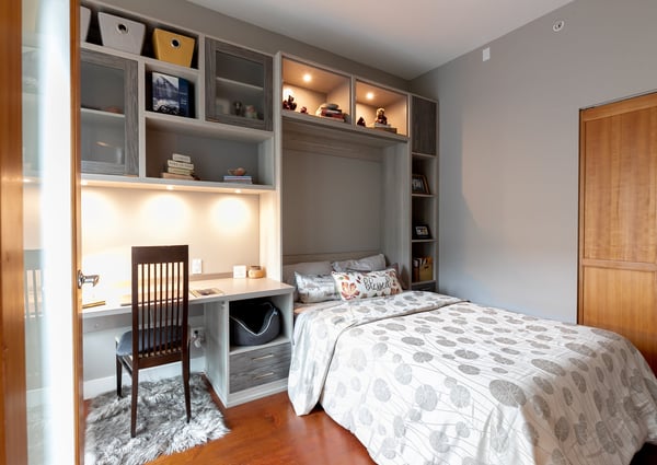 Custom wall bed beside a built in desk with shelving and recessed lighting