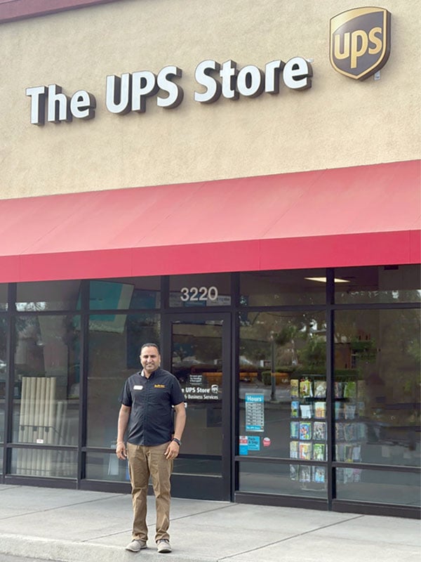 Man in The UPS Store uniform standing outside of a The UPS Store location