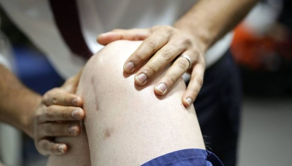 Consultant examining a patients knee