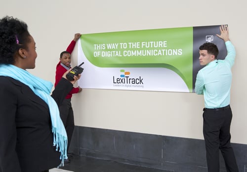 Meeting planner hanging a banner printed from FedEx Office