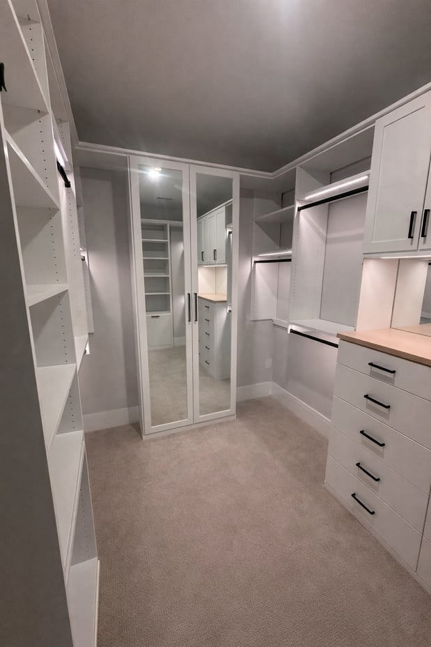 Custom Primary Walk in Closet in Dove with drawers, lighting, hanging, shelving, and doors.