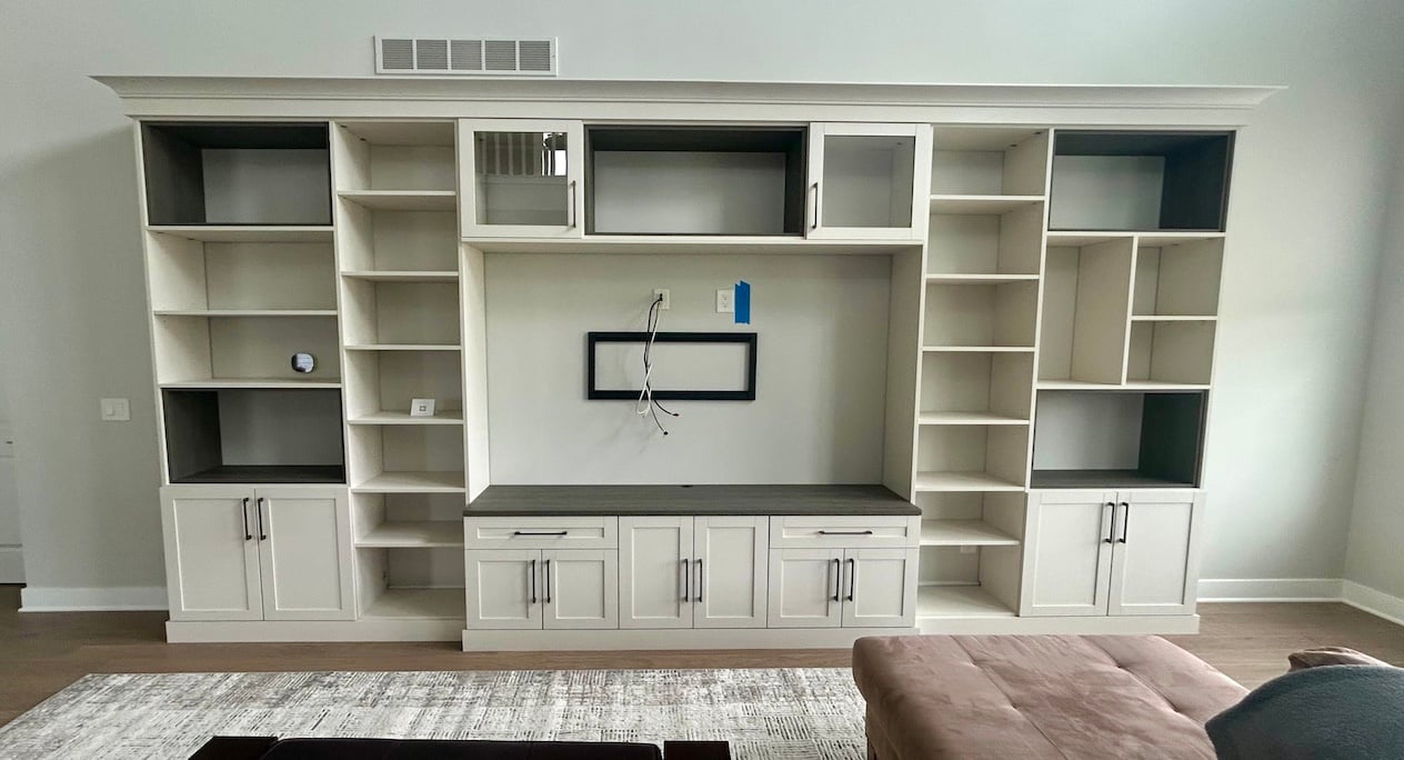 light wood media center with shaker cabinets and open shelving, dark accent shelves, and a centered TV mount