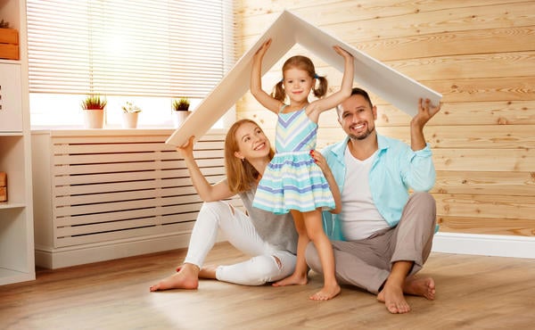 family of three posing with a roof over their heads symbolizing home insurance coverage