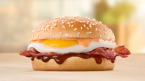 The Bacon & Egg Bun on a brown surface with a blurred background