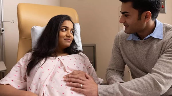 Expecting father with hand on expecting mother's pregnant stomach