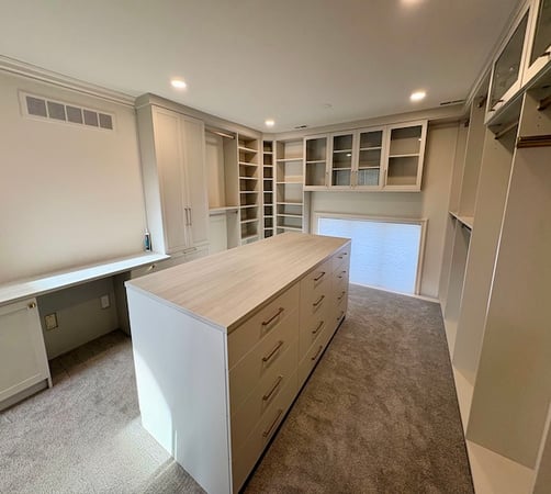 Bright walk-in closet with center island, custom shelving, drawers, and built-in cabinets for elevated closet organization in Rochester, Michigan