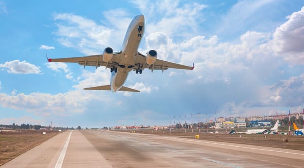 白い旅客機が、素晴らしい白い雲の中、空港の離陸滑走路の上空を飛んでいく