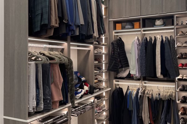 Dark wood custom walk-in closet with double-hang clothing storage, shelving, drawers, and organized wardrobe accessories.