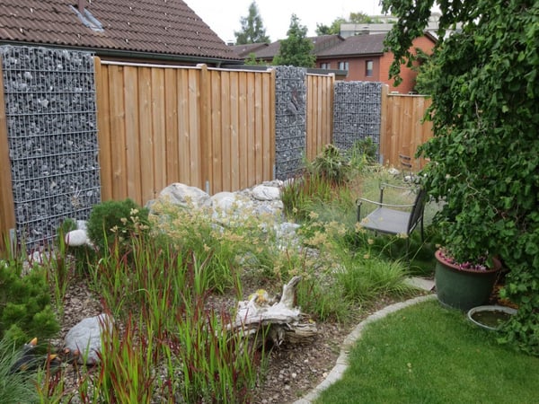 Verspielter Sichtschutz mit Holz und Stein Elementen von garbatec ag Gartenbautechnik und Gartenpflege in Beringen