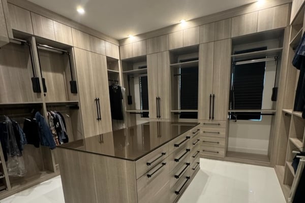 Custom master closet in Pietra finish with matte black hardware, bronze gloss glass countertops, black in-surface power station, motorized wardrobe lifts, microfiber jewelry inserts in ebony and oyster, and Everstyle shirt drawers with integrated pulls.