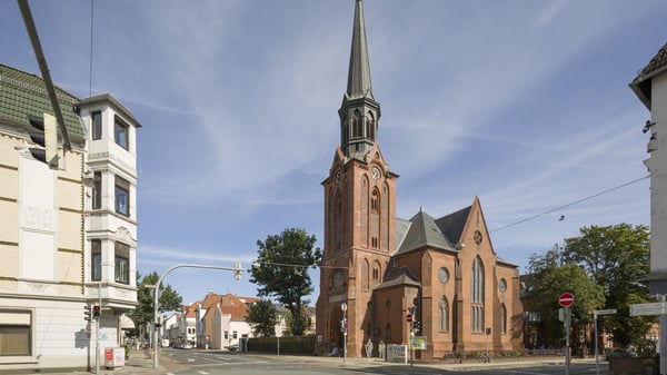 Das Kirchengebäude an einer Straßenkreuzung mit Wohnhäusern.