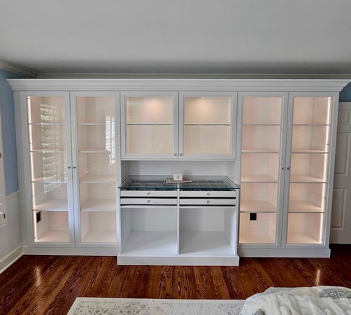 bedroom wardrobe and closet storage with white cabinets and integrated lighting