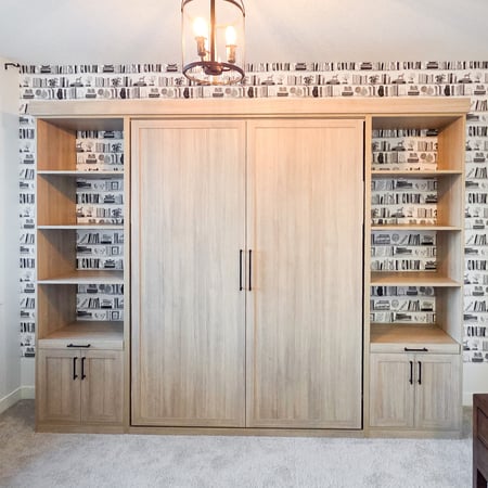 Wall bed in a natural wood finish with open shelving and lower cabinets.