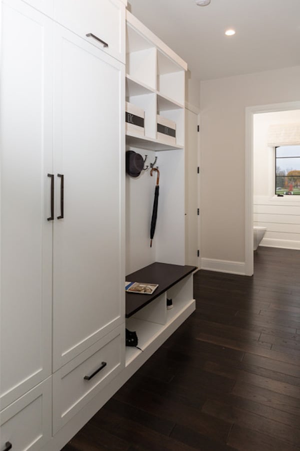 Custom family mudroom with white doors and shelves plus bench seating.