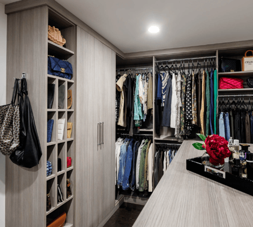 Img 6 California Closets Westchester County NY Gray Walk-in Closet Full Room Dressing Room with Double Hanging Dedicated Shoe Wall with Lighting and a Center Island with Black Leather Jewelry Drawers