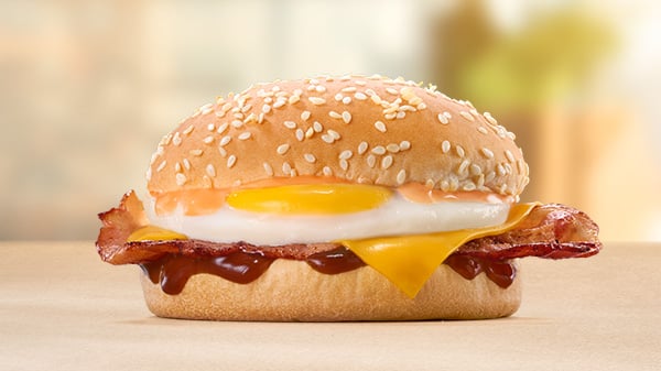 The Bacon, Egg & Cheese Bun on a brown surface with a blurred background