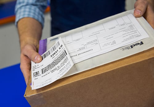 Man holding box, FedEx envelope and FedEx label