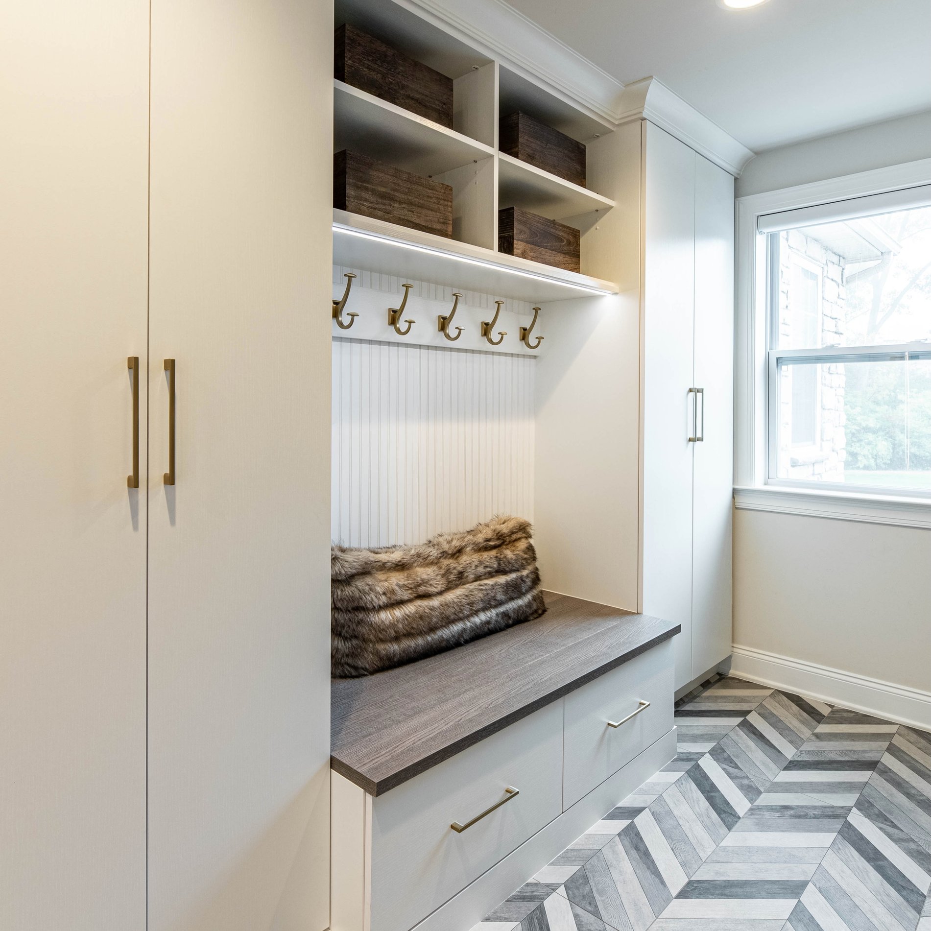 Custom mudroom storage with built-in bench, coat hooks, and upper cubbies.