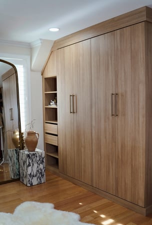 Custom built-in wardrobe in an oak finish with floor-to-ceiling storage by California Closets Greenwich, Connecticut.