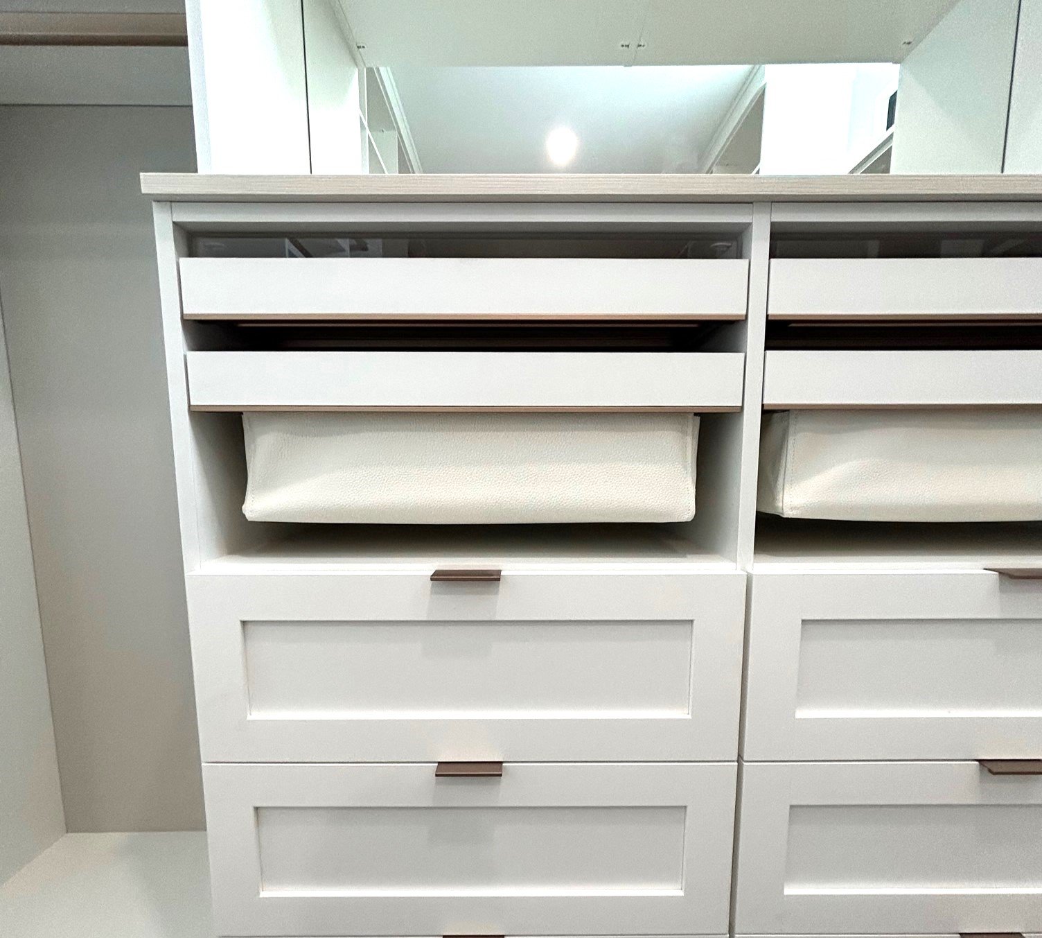 A bank of white drawers with vegan leather baskets
