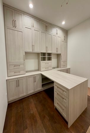 Custom craft room storage system featuring built-in cabinets, custom closets, drawer organization, shelving, and a multifunctional workspace island. This home office and crafting storage solution includes floor-to-ceiling cabinetry, closet organization, and custom storage systems designed for functional home organization by California Closets.