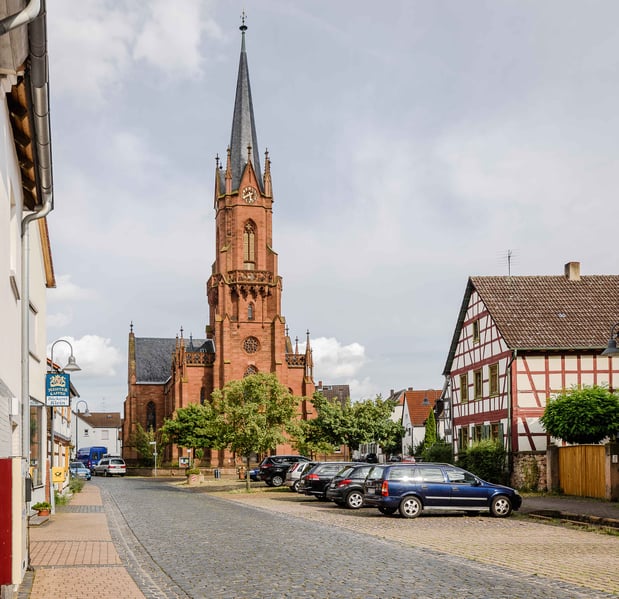 Der älteste Nachweis über ein Gotteshaus in Langstadt stammt aus dem Jahre 1482: Erwähnt wird eine Kapelle, die in der Ortsmitte stand. 1523 wird die Kapelle erweitert, 1561 wird Langstadt selbstständige Pfarrei. Im 18. Jahrhundert folgen weitere Erweiterungen. 1877 wird das Kirchengebäude abgebrochen, weil es zu klein geworden war. An dessen Stelle entsteht von 1878 bis 1880 der große neugotische Bau der heutigen Pfarrkirche.