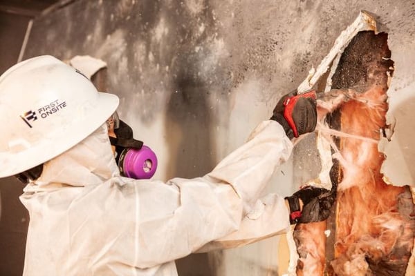 Close-up of restoration pro in respirator removing fire damaged insulation.