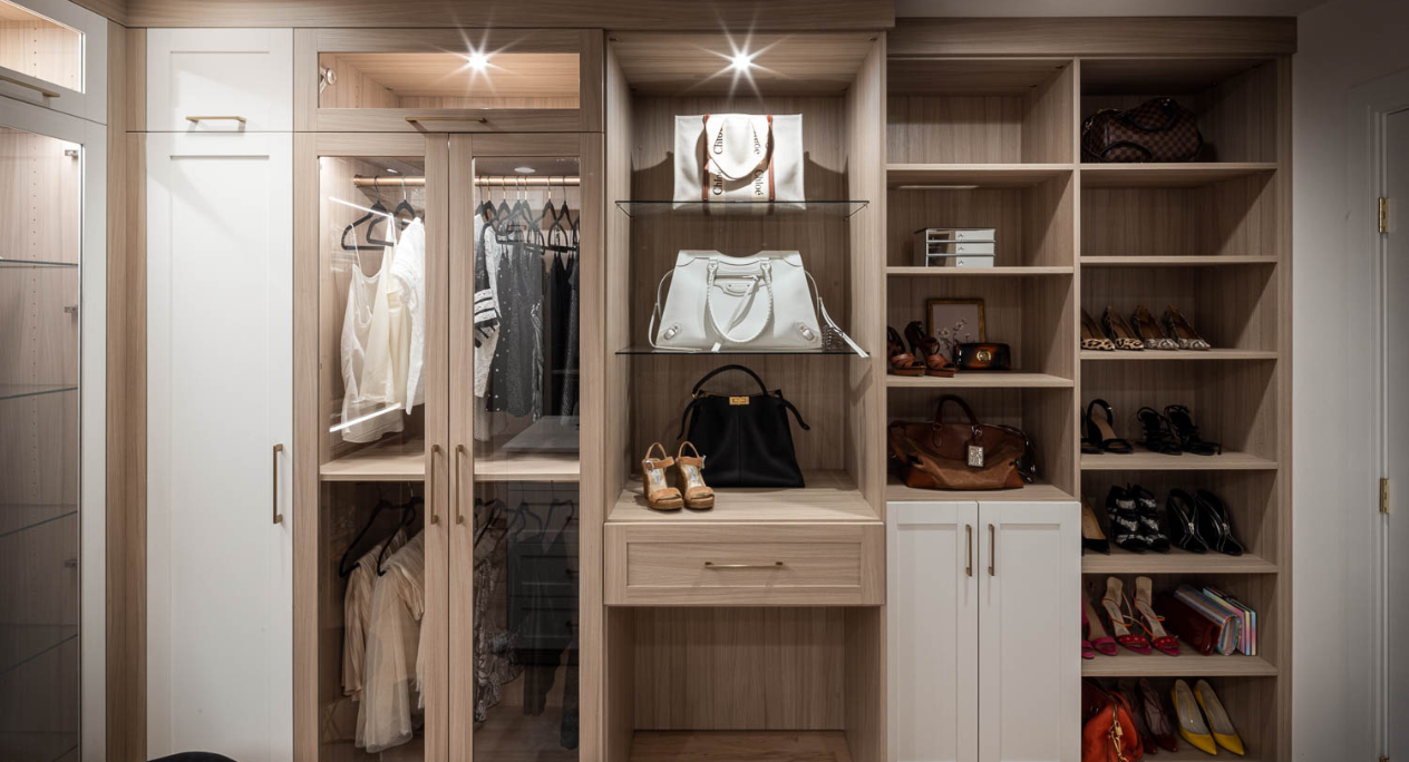 Img 9 California Closets Westchester County New York Two Toned White and Beige Large Walk-in Luxury Closet with Glass Shelving, Glass Doors, Lighting, and a Custom Center Island with Custom Jewelry Drawers