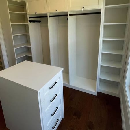 A custom walk-in closet with abundant shelving and an island of drawers.
