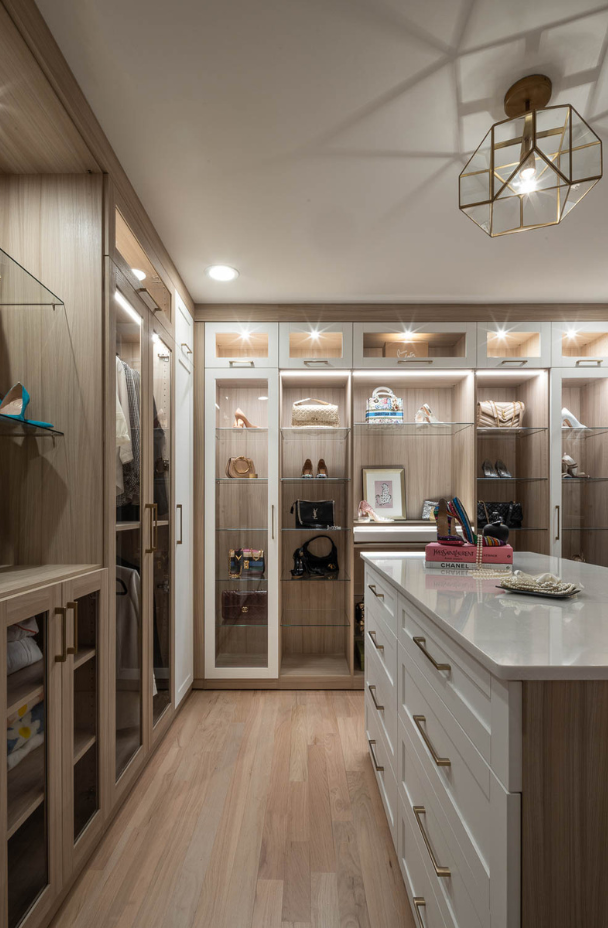 Img 8 California Closets Westchester County New York Two Toned White and Beige Large Walk-in Luxury Closet with Glass Shelving, Glass Doors, Lighting, and a Custom Center Island with Custom Jewelry Drawers