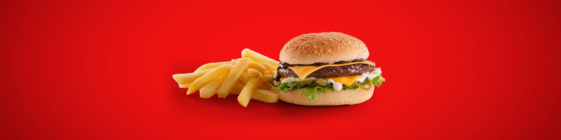 Burger with cheese, BBQ sauce and mayo, next to a portion of chips, set against a red background.