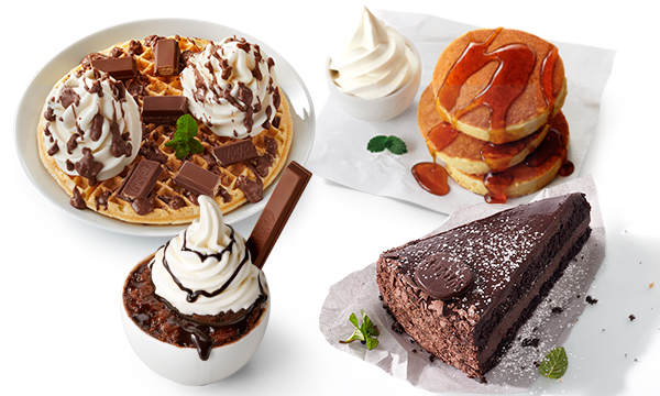A collection of desserts including waffles, flapjacks and cake against a white background.