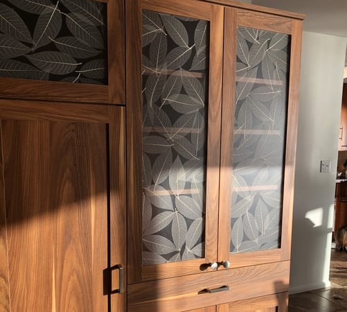 A warm wood finish and etched resin inserts add sophistication to this built-in wardrobe with drawers and cabinets.