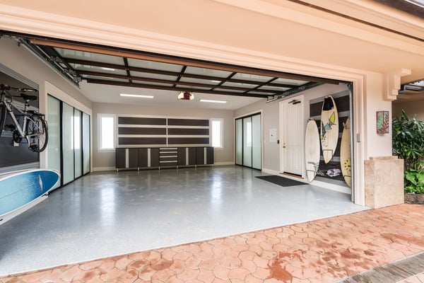 Custom storage solution for a two-car garage provides organized storage for sports equipment, including bikes and surfboards.