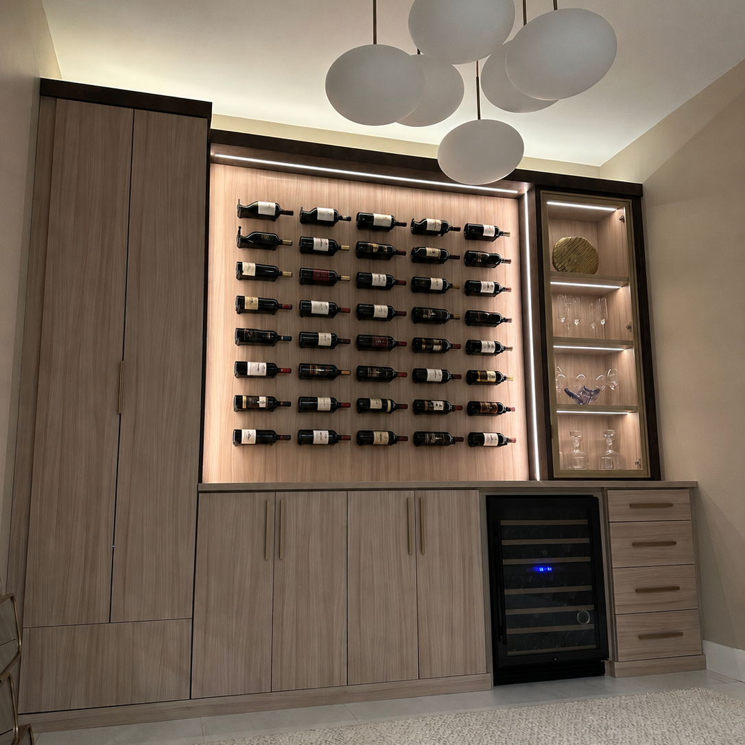 Modern custom wine wall with wood cabinetry, wall-mounted bottle storage, illuminated shelving, drawers, and a built-in wine refrigerator.