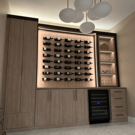 Modern custom wine wall with wood cabinetry, wall-mounted bottle storage, illuminated shelving, drawers, and a built-in wine refrigerator.