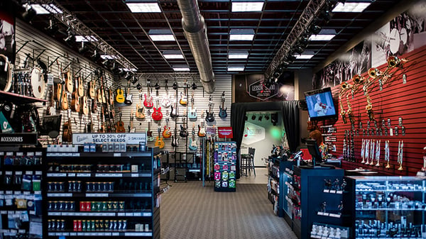 A corner wall of guitars where acoustic guitars line the left wall and varied colors of electric guitars line the back wall.