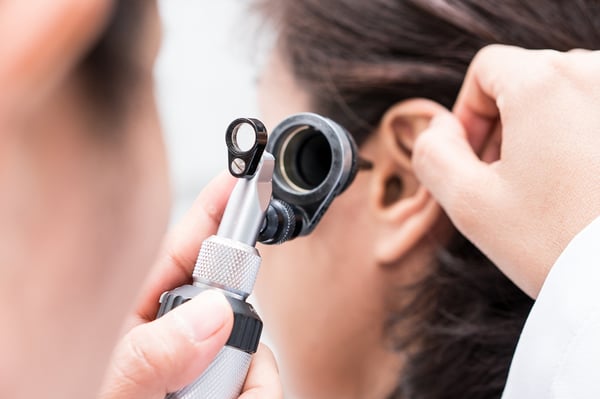 Audiologist uses an otoscope to check for fluid in his patient's ear.