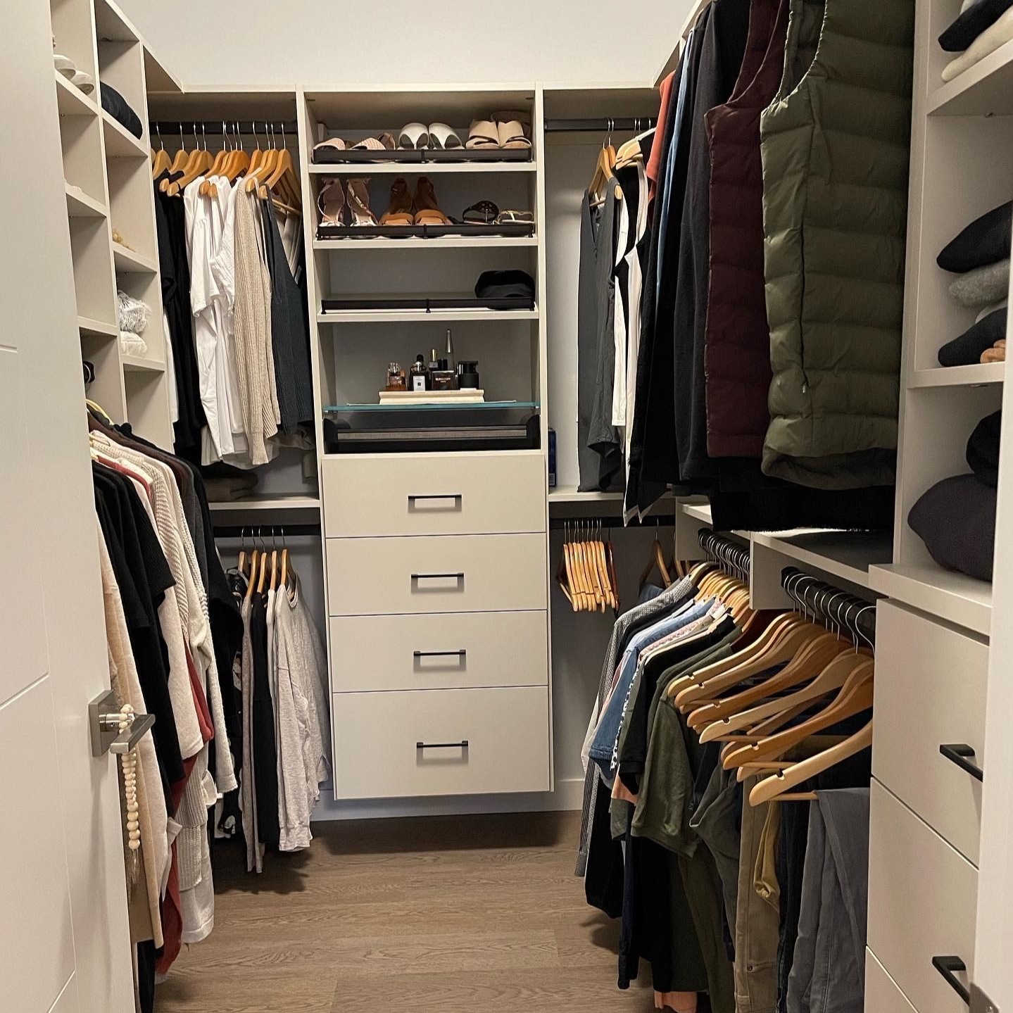 Walk-In closet design an off white finish with black hardware. There is a combination of double hang, long hang, shelving and drawers.
