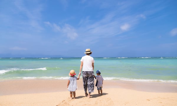 沖縄の浜辺を歩く母親と双子の後ろ姿