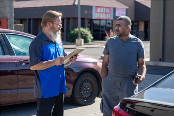 Picture of Grease Monkey team member greeting a customer in the parking lot at Bell Road Phoenix location
