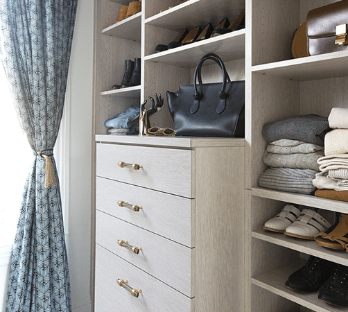 Close up of light grey custom walk in closet shelves with organized clothes and accessories
