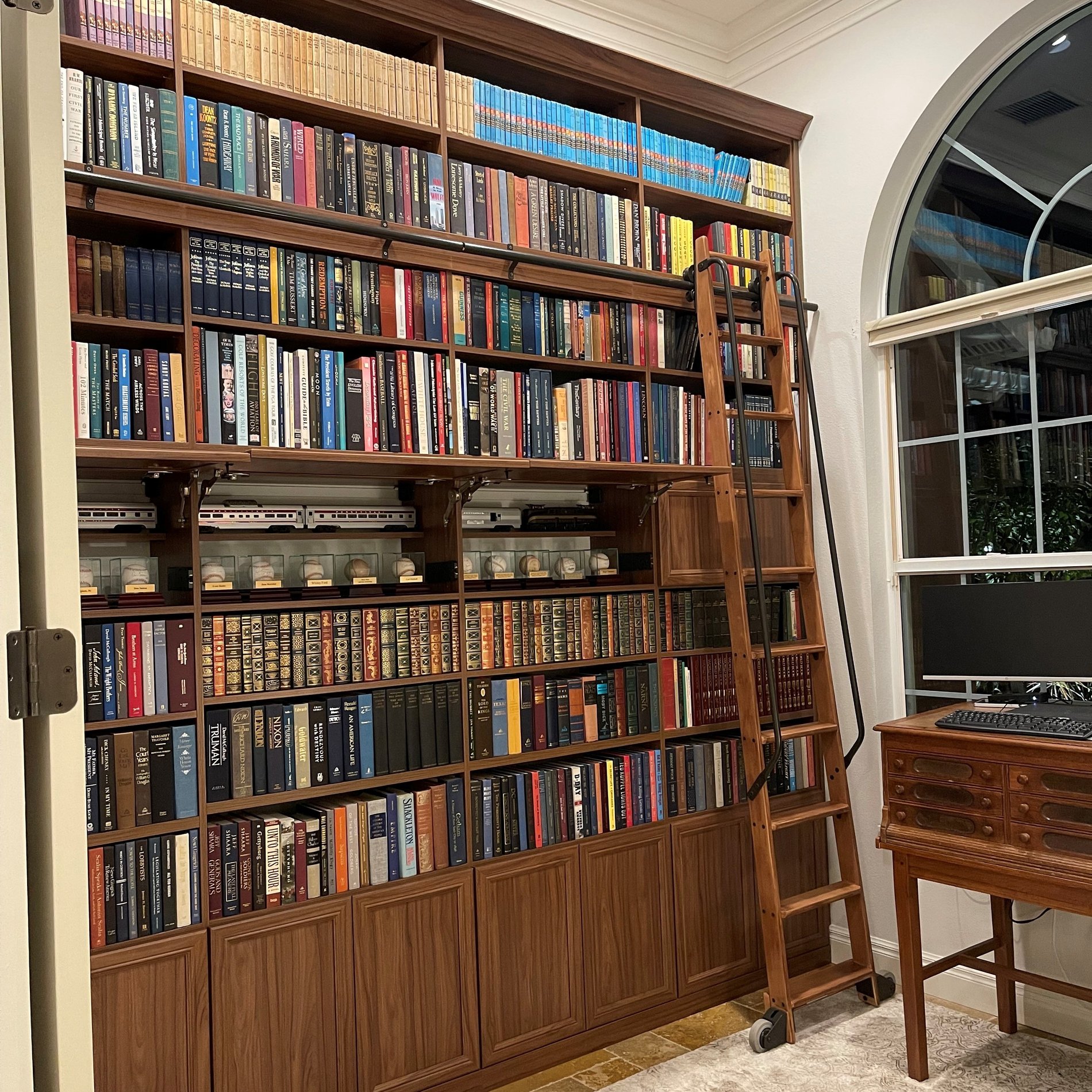 Custom library in Sienna finish with sliding ladder, Lexington modern-miter door fronts, and stealth locks.