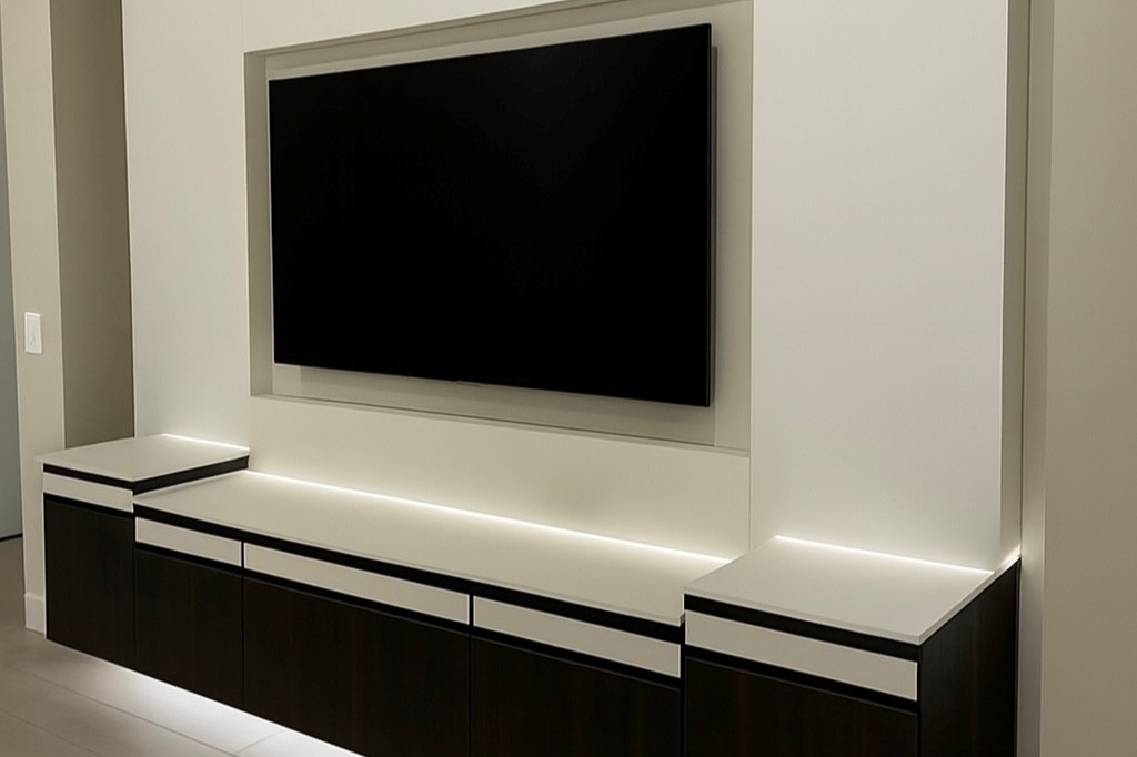 Custom media center in cappuccino and bianco finishes with gold hardware, Everstyle drawers, and backlit chroma countertops.
