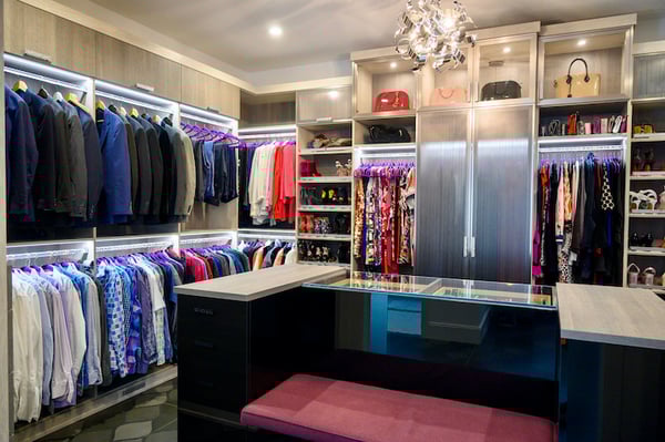Custom walk-in closet with bench seating and black acrylic closet island.