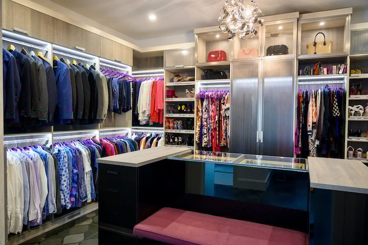 Custom walk-in closet with bench seating and black acrylic closet island.
